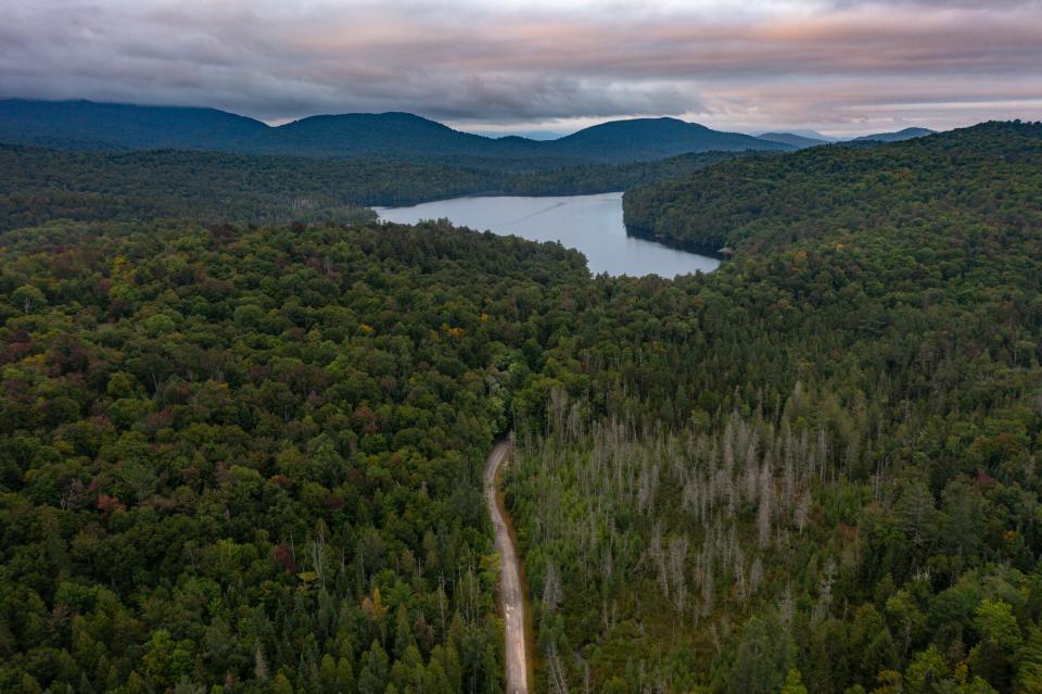 An aerial view of a dirt road leading to a large pond.