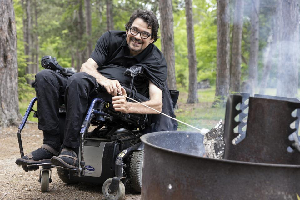 A man in a wheelchairs toasts a marshmallow.