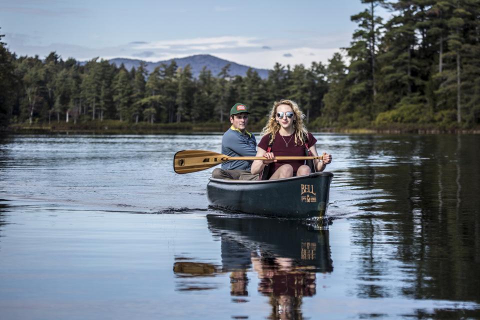 Two people canoeing on a lake surrounded by trees