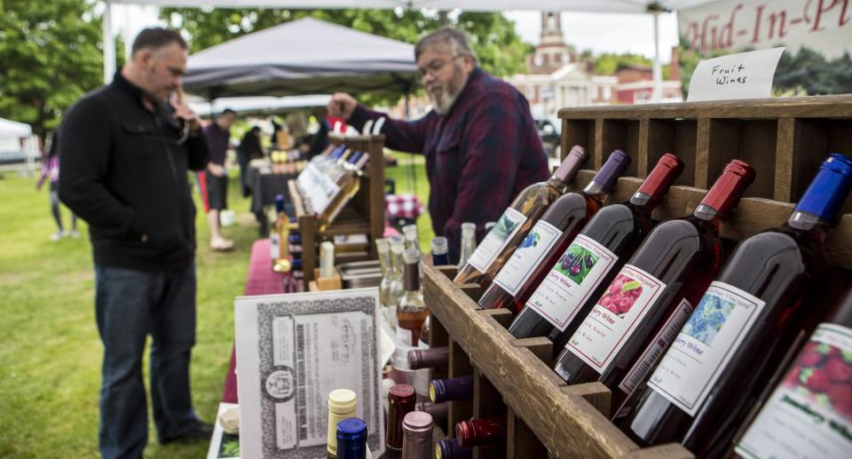 A man chooses from wines at a farmer's market.