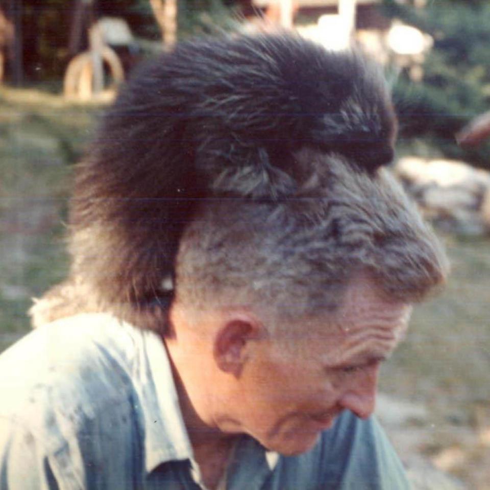 A man with a porcupine sitting on his shoulders.