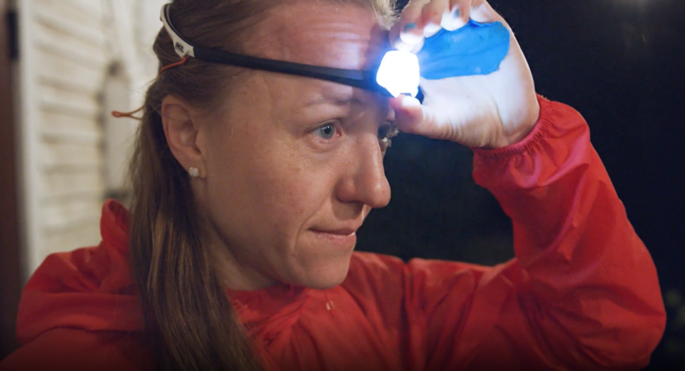 A woman turns on a headlamp in the dark