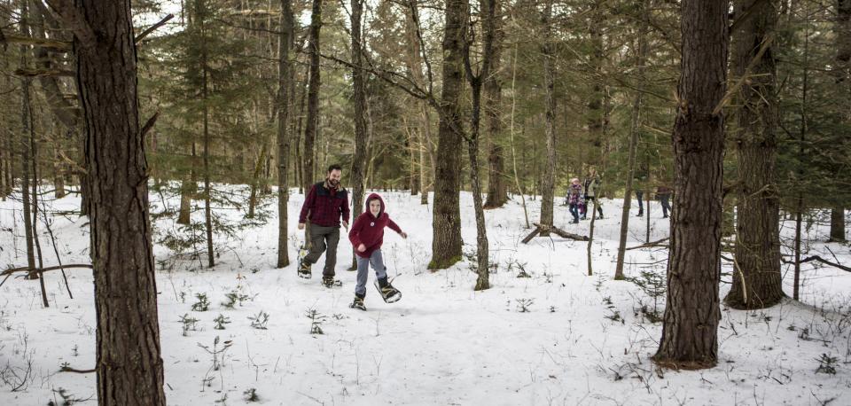 A family on a snowshoe hike, the leader a young boy grinning from ear to ear