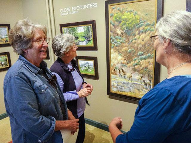 artist Sandra Hildreth (right) shares some interesting stories about the paintings