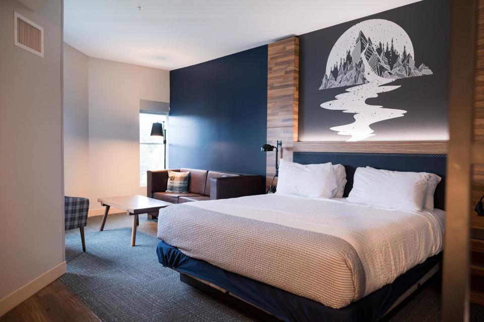 A clean hotel room with a mountain tapestry above the bed.
