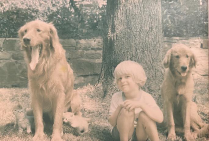 Jason Smith pictured as a child next to two golden retrievers