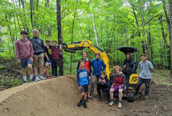 A group of young bikers pose next to an almost built pump track