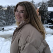 A woman smiles at the camera in a snowy image. 