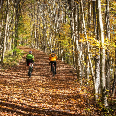 two cyclists on a backcountry trail on a sunny fall day