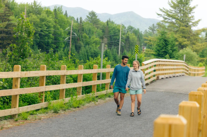 Couple walks the trail with new fence and mountain view