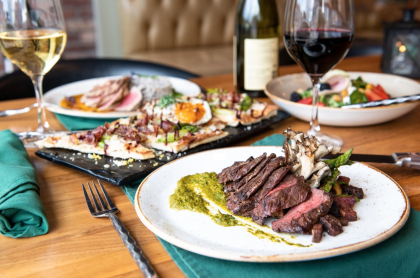 Dinner table set with several courses and wine