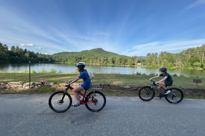 two road cyclists with pond in the background 
