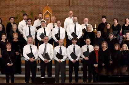 The mens choir stands on stage with white shirts