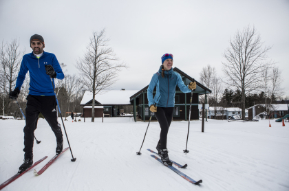 Couple skiing at view of the Dewey Mountain Lodge in the background.