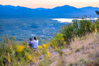 Two people look over at a view of mountains and a lake