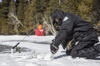 Someone cutting a hold in the ice for fishing
