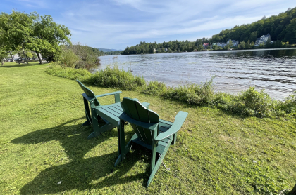 two adirondack chairs on the edge of a lake