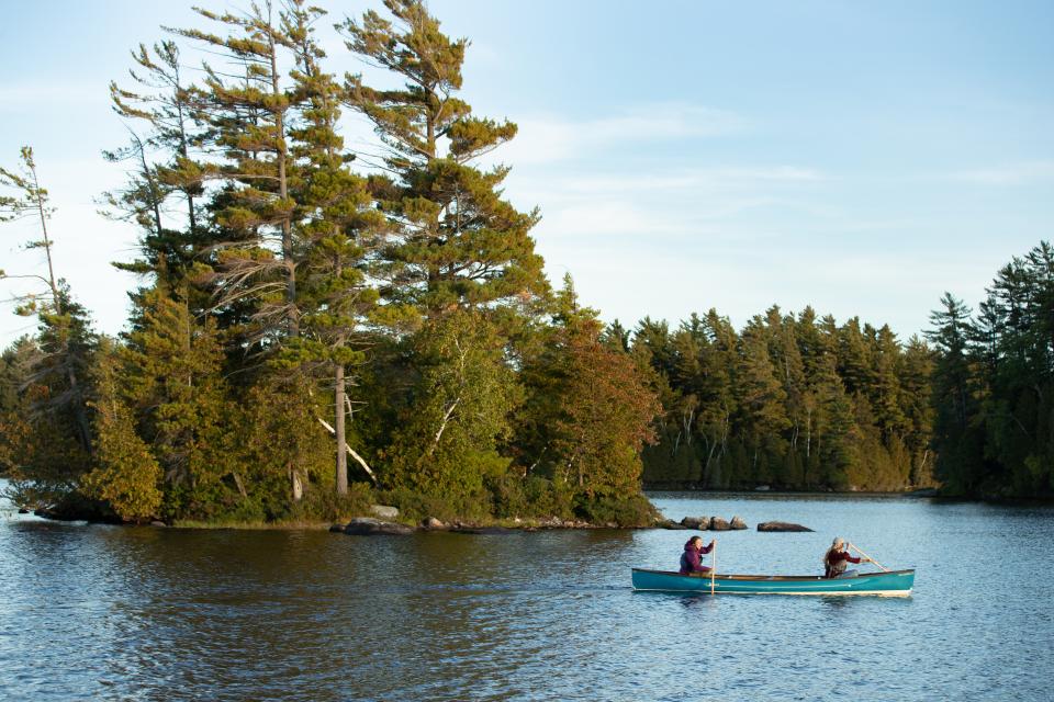 Two paddlers passing one of the smaller Saranac islands in a canoe.