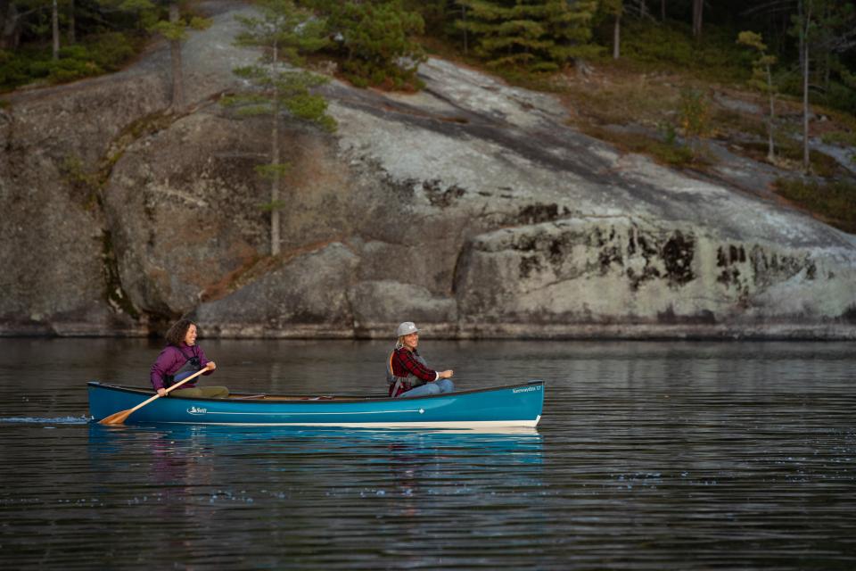 Two people paddle in a blue canoe on Lower Saranac Lake.