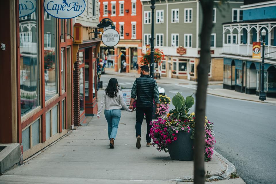 A couple walks past buildings in Saranac Lake's downtown