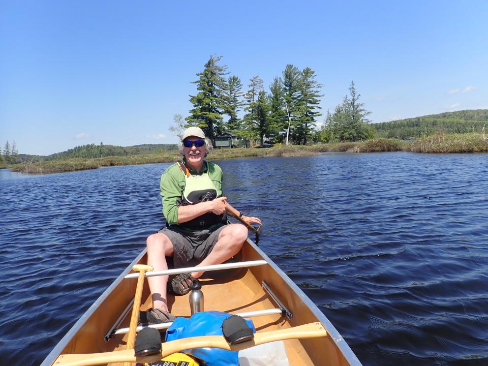 Man smiling at the front of a canoe