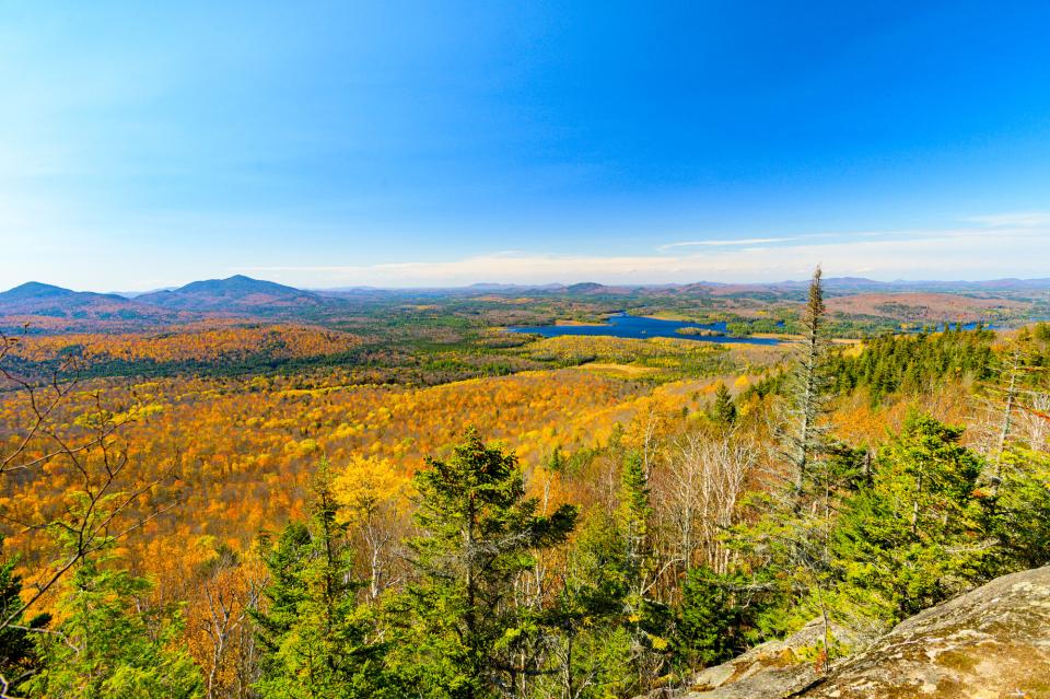 An aerial view of a mountain range in fall at peak foliage.