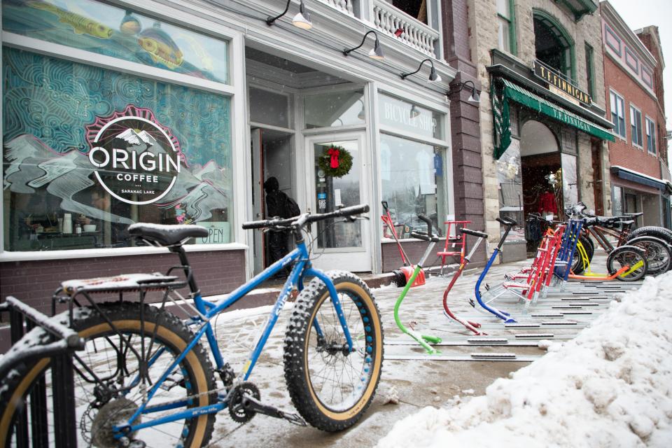 Fat tire bikes stand on the snowy sidewalk in front of Origin Coffee in Saranac Lake.