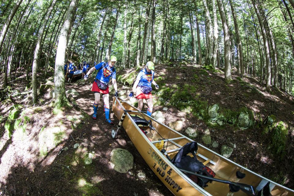 A team navigates one of the carries with their canoe in the Adirondack Canoe Classic