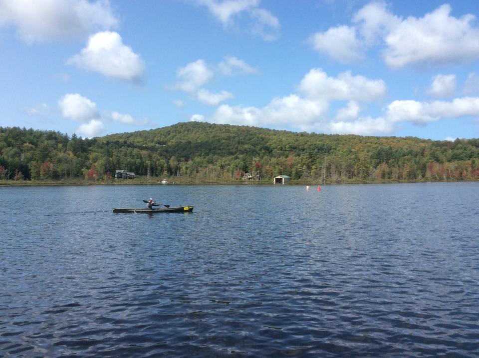 A man in a black canoe paddles across a lake during the Adirondack Canoe Classic