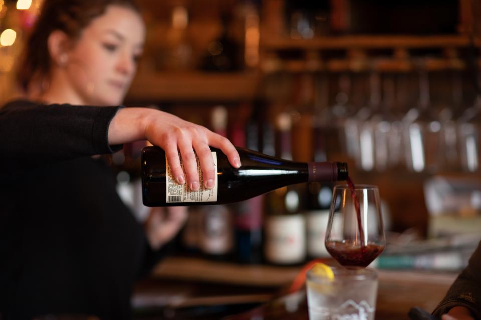 A bartender pours a glass of red wine at one of Saranac Lake's bars