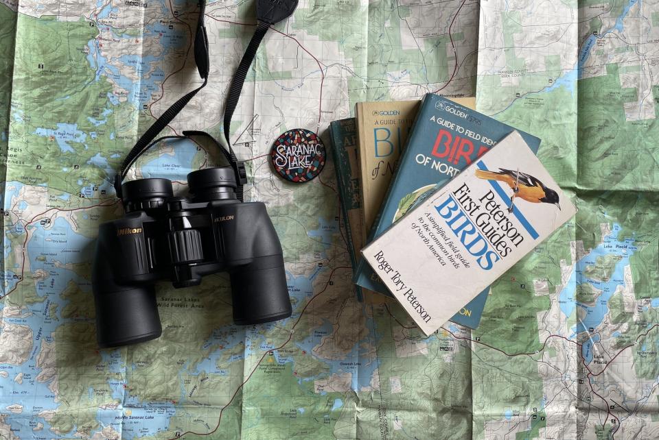 A map with binoculars and bird watching books stacked on top of it.
