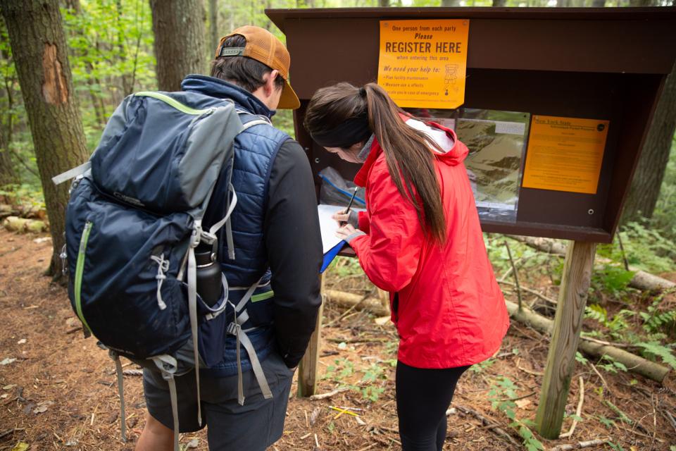 A couple signs into a hiking trail register.