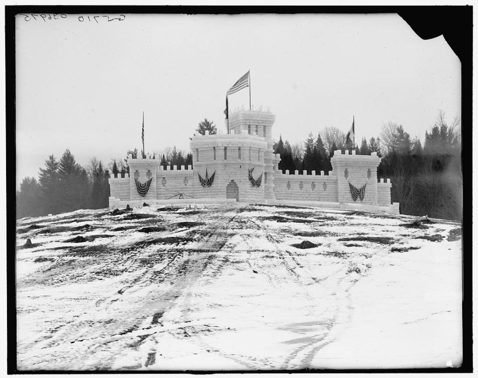 Black and white vintage image of an early, large ice castle on a hill.