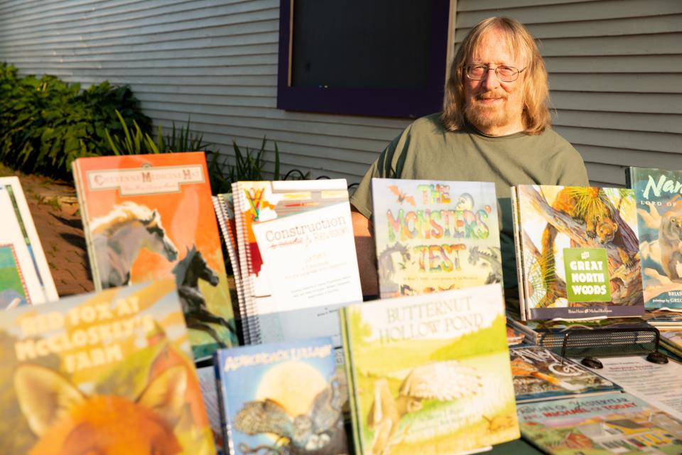 A man sits behind a table holding children's books