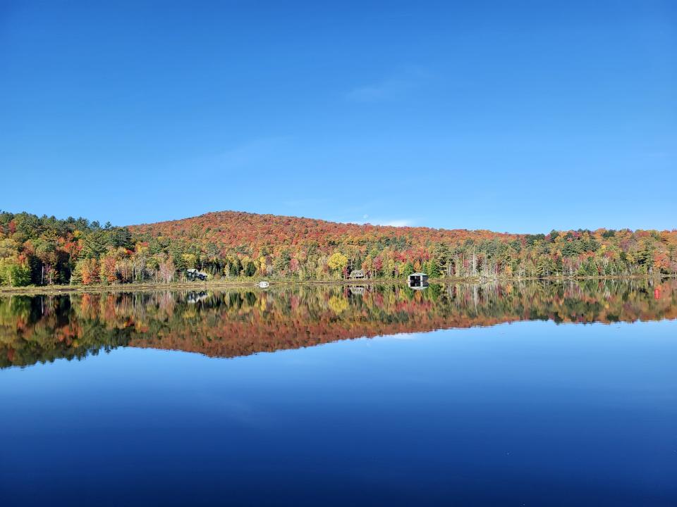 A view across a body of water, with brilliant fall foliage on the distant shore
