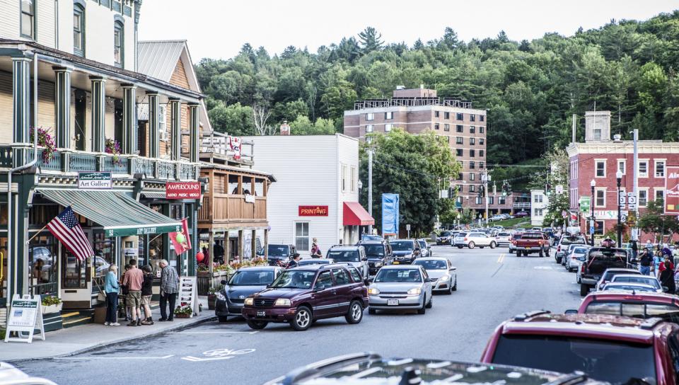 Cars are seen driving past businesses in downtown Saranac Lake