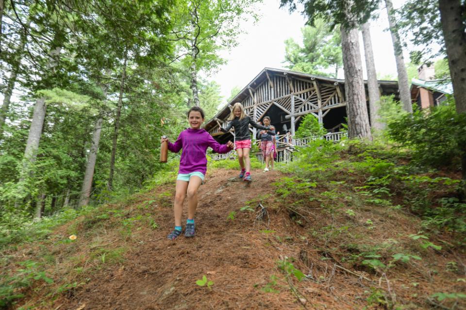 Three children campers at Eagle Island Camp walking through the forest. Photo provided by Erika Bailey.