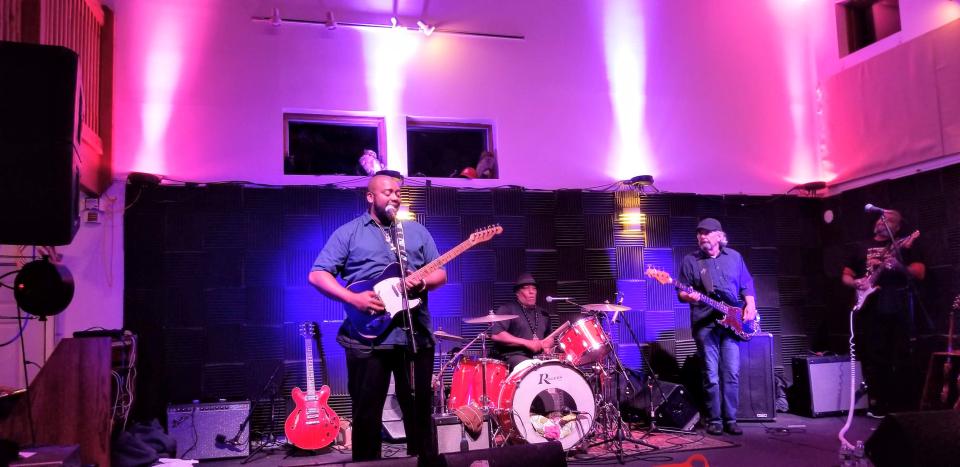 A band plays in colorful lighting at an indoor venue.
