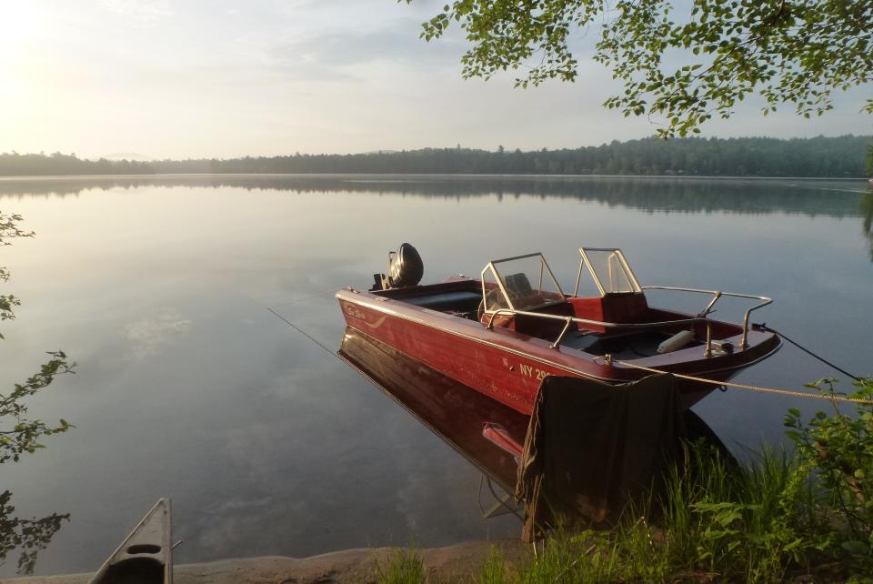 Small motorboat on a calm pond at sunrise.