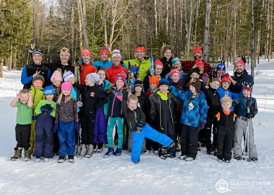 A group of kids stand together for a group photo while dressed in their winter gear outside in the snow