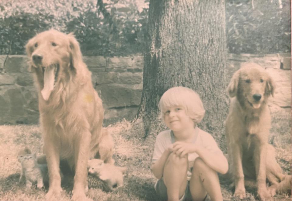 Jason Smith pictured as a child next to two golden retrievers