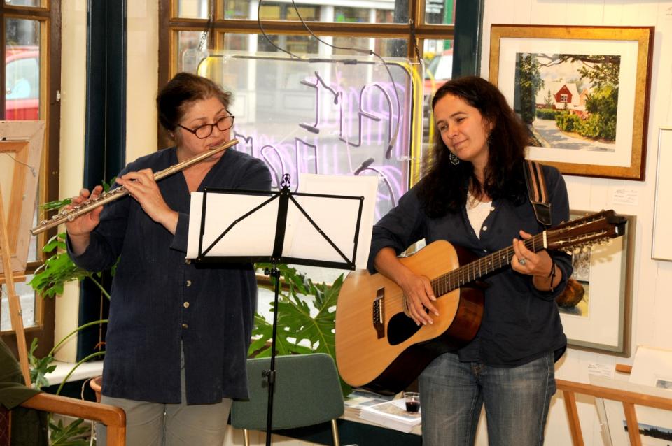 Two women play a flute and guitar.