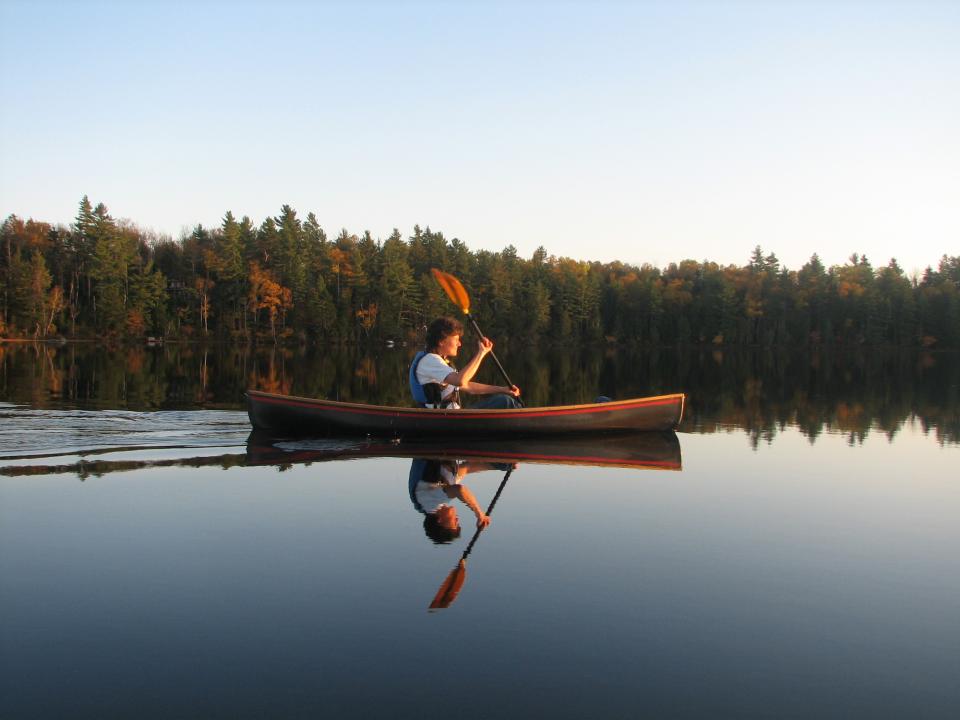 A woman paddling in a solo canoe.