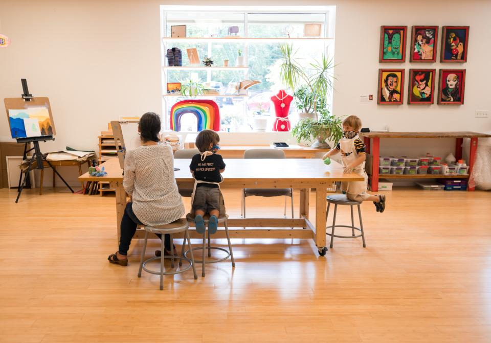 Woman and kids sit at table making art