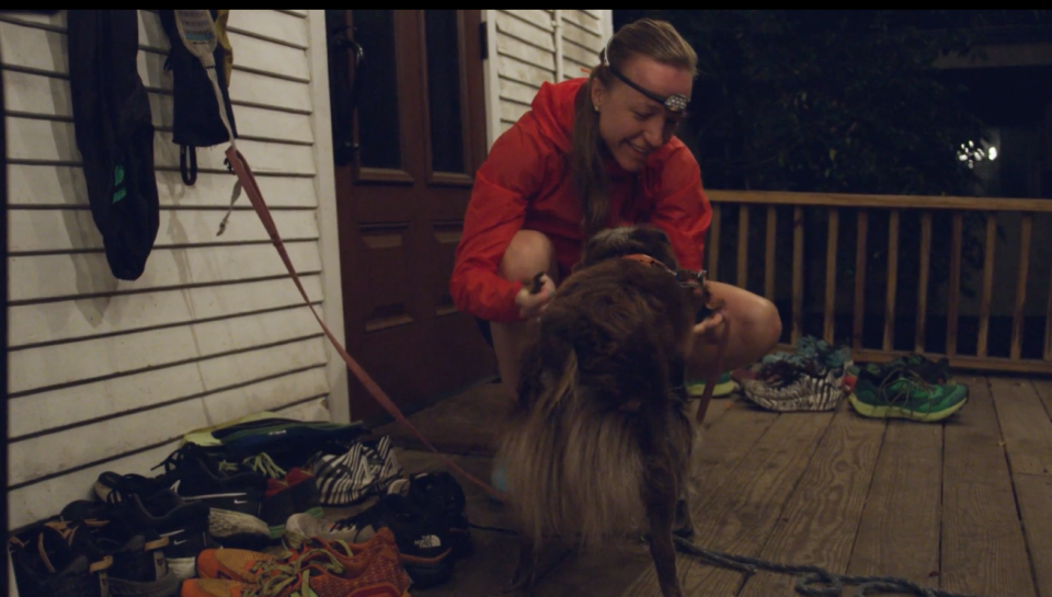 A woman puts a collar on a dog as they prepare to run together