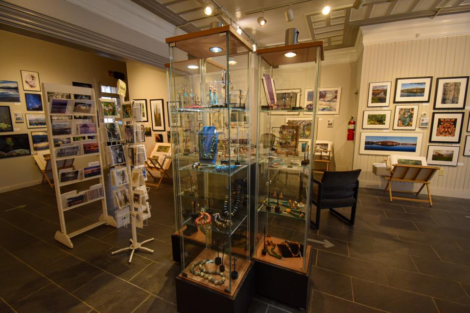 Displays at an art gallery: jewelry, paintings, photographs, and post cards.