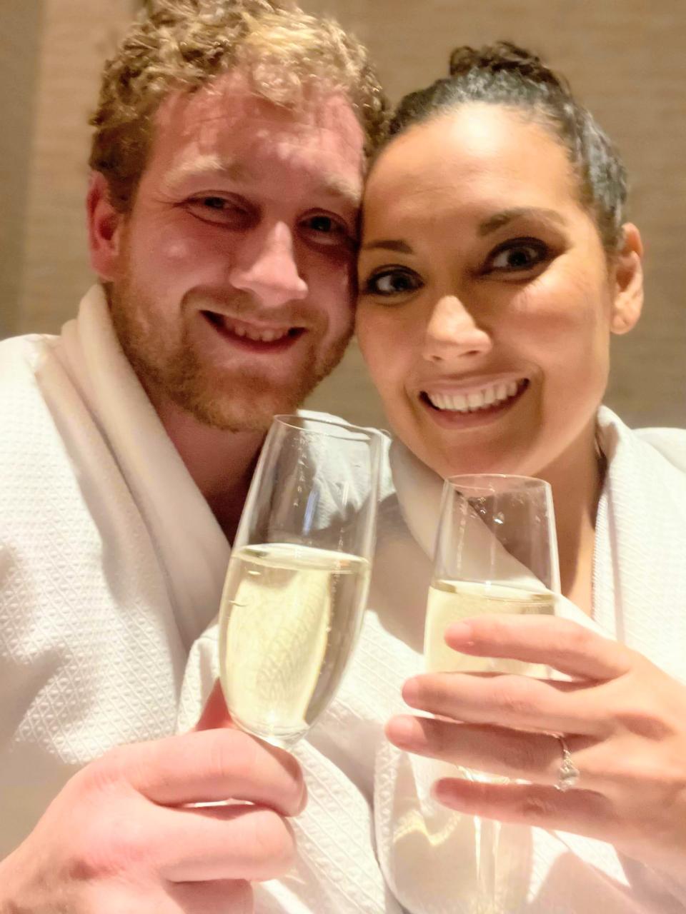 Two people in spa bath robes drink champagne while waiting to get a massage