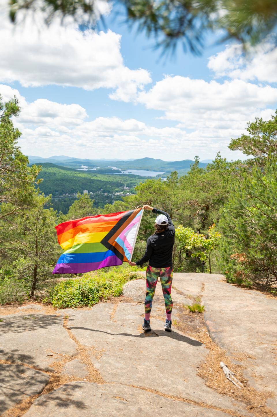 A woman stands on Mount Baker holding a trans pride flag.
