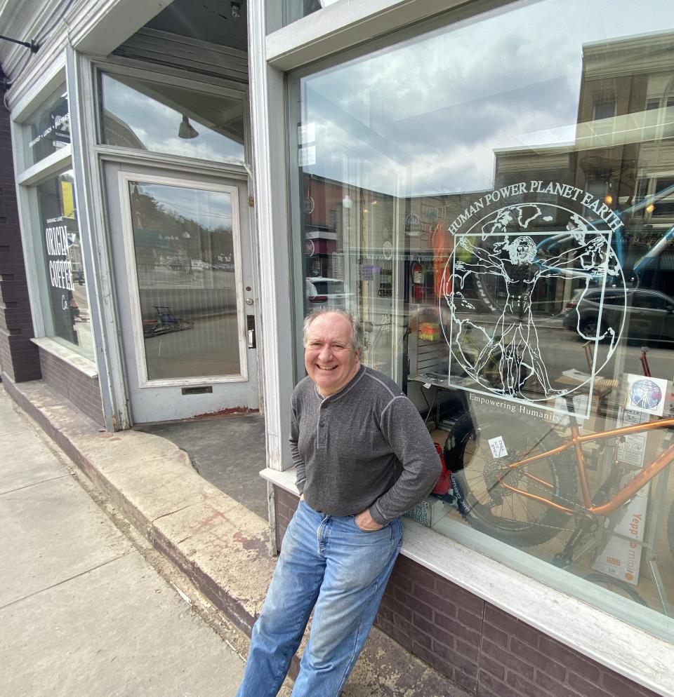 owner poses in front of his shop