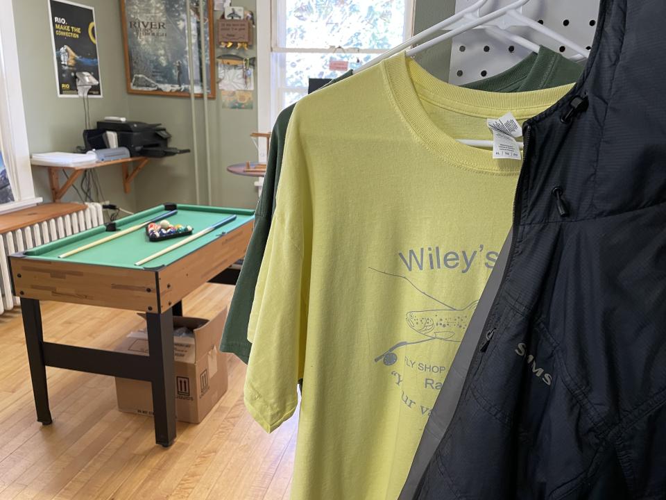 A small pool table stands beyond a tshirt display.